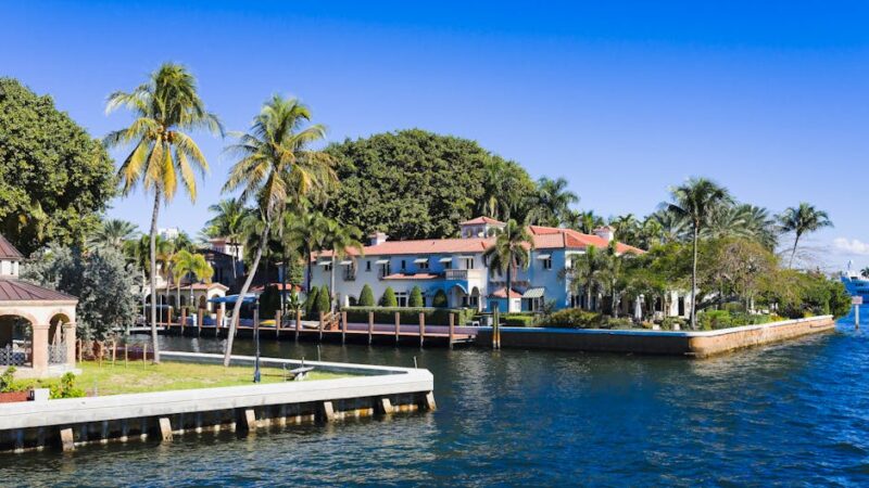 Beautiful tropical homes along a canal with palm trees and clear blue sky in Fort Lauderdale, Florida.